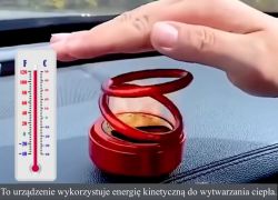 Ręka nad czerwonym urządzeniem na desce rozdzielczej z widocznym termometrem.