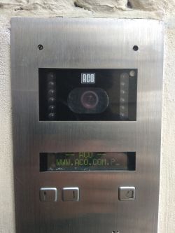 Panel wideodomofonu marki ACO z ekranem LCD i przyciskami.