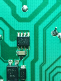 Zbliżenie na płytkę drukowaną z widocznymi elementami elektronicznymi i ścieżkami.