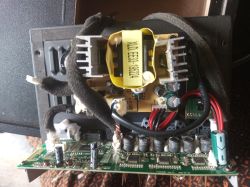 Inside view of an audio amplifier or powered speaker showing the mainboard, electronic components, and a transformer.
