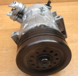 Kompresor klimatyzacji z samochodu Opel Corsa D na drewnianym tle.