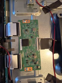 Close-up of T-con board inside JVC TV with visible ribbon cables