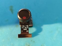 Camera module with lens on flexible ribbon cable on blue background