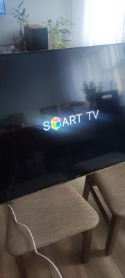 Telewizor z logo Smart TV i widocznymi cienkimi pionowymi kreskami na ekranie.