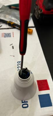 Screwdriver inserted inside the case of a smart light bulb.