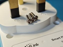 Three metal screws placed on a British-style electrical plug casing.