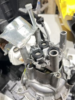Image of an engine with a visible plastic head and bolt, leaking water.