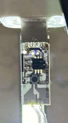 Zbliżenie na płytkę sterującą światełkami LED z widocznym przyciskiem i elementami elektronicznymi.