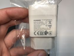 Biała ładowarka sieciowa Huawei trzymana w ręce, widoczna etykieta z parametrami technicznymi.
