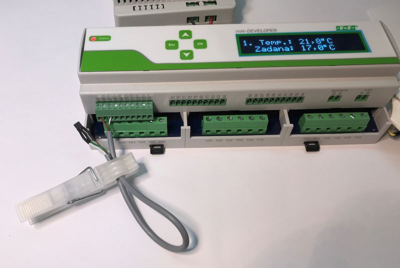 Building automation controller with LCD display and connected temperature sensor.