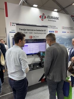 Dwóch mężczyzn ogląda stanowisko firmy Elmark Automatyka z ekranem i urządzeniami sieciowymi