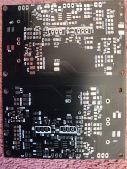 Czarna płytka PCB ze ścieżkami i oznaczeniami elementów, częściowo polutowana