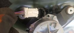 Złącze elektryczne z przewodami fioletowym, czarnym i brązowym podłączone do silnika wycieraczki samochodowej.