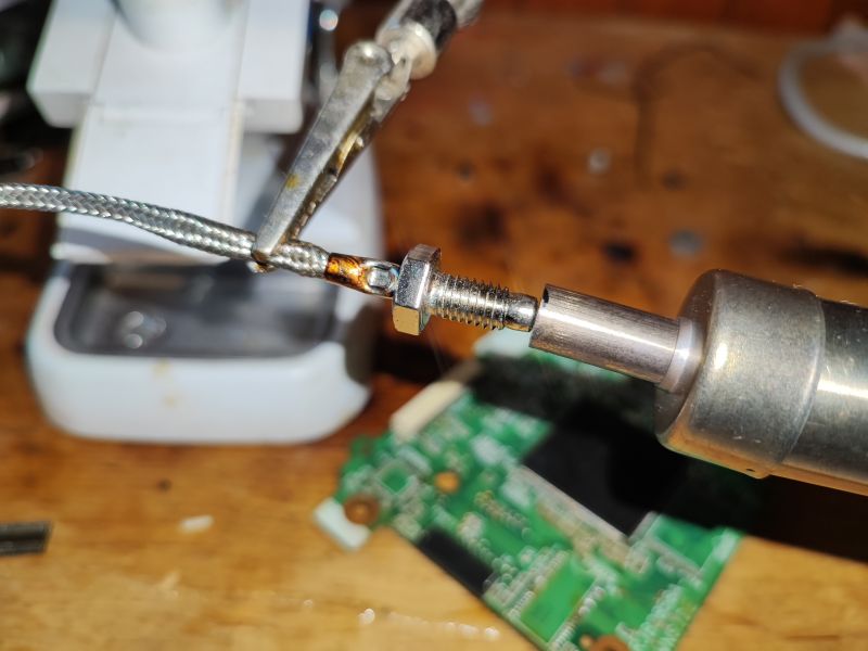 Close-up of a type K thermocouple connected to a screw in a workshop setting.