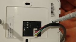 Zbliżenie na moduł elektroniczny z wtyczką i wielokolorowymi przewodami w białej obudowie