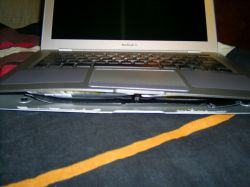 Zbliżenie na MacBooka Air z wypchanym spodem obudowy przez spuchniętą baterię