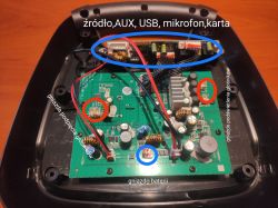 Wnętrze urządzenia elektronicznego z zaznaczonymi elementami: źródło, AUX, USB, mikrofon, karta, gniazda podpięcia i podświetlenia głośników oraz gniazdo baterii.
