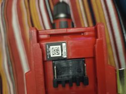Zbliżenie na etykietę z kodem QR i numerem seryjnym na czerwonym elektronarzędziu