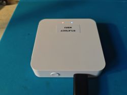 White electronic device with two LEDs on top, one red and one blue, and a button on the side.