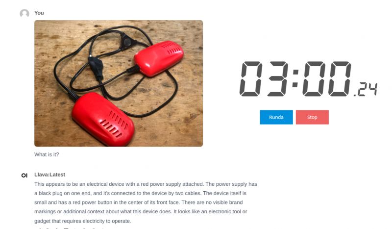 Red electrical device with a power supply connected on a wooden table, with a timer reading 3:00.24 and buttons labeled Runda and Stop.