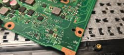 Zbliżenie na płytę główną laptopa z widocznymi elementami elektronicznymi i zarysowaniami.