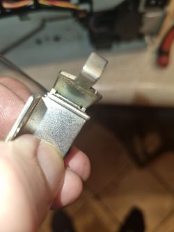 Zbliżenie na metalowy element trzymany w palcach, z widoczną sprężynującą blaszką
