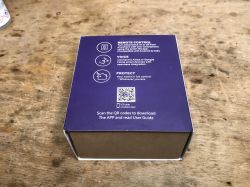 Smart WiFi Socket SWP86-01OG Packaging Purple packaging box of a smart WiFi socket on a wooden surface, showing icons and a QR code.