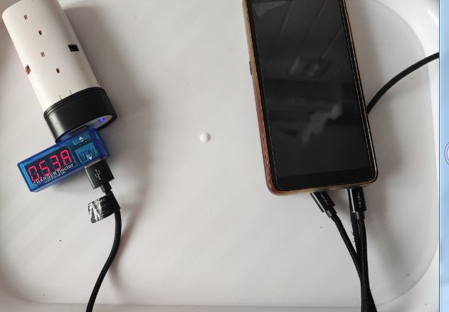 Ładowanie telefonu za pomocą prowizorycznego zestawu z ogniwem i miernikiem napięcia
