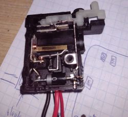 Widok wnętrza przełącznika z widocznymi elementami elektronicznymi na kartce z notatkami technicznymi.