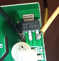 Close-up of an AMS1117 3.3V chip mounted on a PCB with attached wires.