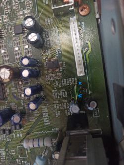 A circuit board fragment with capacitors, resistors, and a white connector visible.