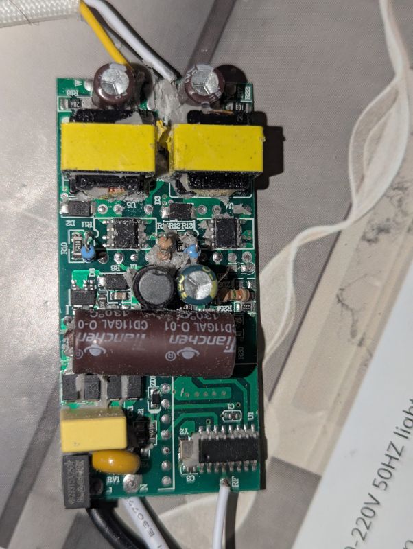 Zbliżenie na płytkę PCB z elementami elektronicznymi, m.in. kondensatorami i cewkami.
