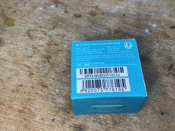 Sonoff Mini R2 Packaging on Wooden Surface Sonoff Mini R2 module packaging on a wooden surface.