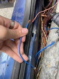 Car Electrical Wiring Repair The image shows two electrical wires held by a person, they are soldered and partially exposed. A bundle of wires is visible in the background.