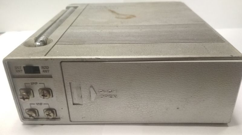 Przód małego urządzenia elektronicznego z pokrywką i złączami antenowymi.