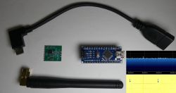 Zestaw elektronicznych komponentów: kabel OTG, antena, płytka Arduino Nano, moduł RF i widmo sygnału.