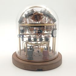 Zegar Nixie pod kopułą szklaną z widocznymi elementami elektronicznymi.