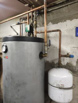 Instalacja grzewcza z manometrem, zbiornikiem ciśnieniowym i rurami miedzianymi.