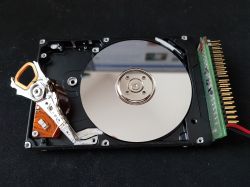 Open old hard disk with visible platter and head.