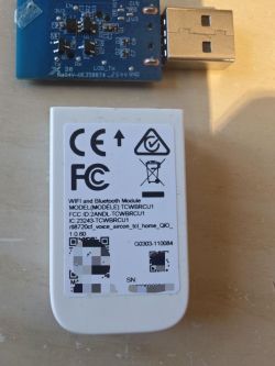 USB circuit board with SMD parts and a white Wi‑Fi/Bluetooth module housing with certification label