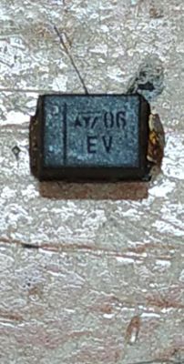 Zbliżenie na czarny komponent SMD z oznaczeniem A7 06 EV na metalizowanej płytce.
