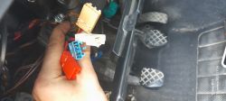 Kolorowe kostki elektryczne pod kolumną kierowniczą samochodu VW Golf 4, trzymane w dłoni nad pedałami.