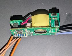 The image shows a disassembled electronic component with a coil and button board on a gray background.