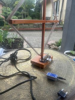 Drewniana rama z nawiniętym przewodem i małym układem elektronicznym na stoliku na zewnątrz