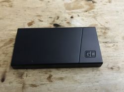 Czarny powerbank z logiem GC (Green Cell) na drewnianym tle.