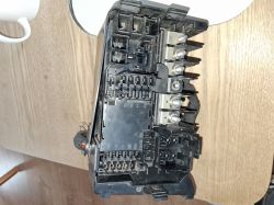 Car fuse box lying on a wooden table.