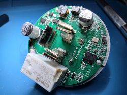 Round PCB with capacitors, a coil, and metal contacts on a blue background