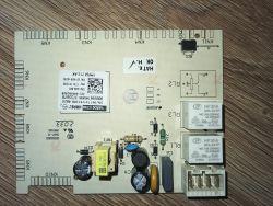 Płytka główna sterująca zmywarki leży na drewnianej powierzchni, widoczne przekaźniki i elementy elektroniczne.