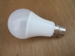 B22 LED Light Bulb on Wooden Surface White LED light bulb with bayonet cap lying on a wooden surface