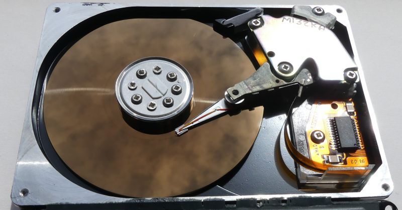 Inside of a hard drive with visible platter and head arm.